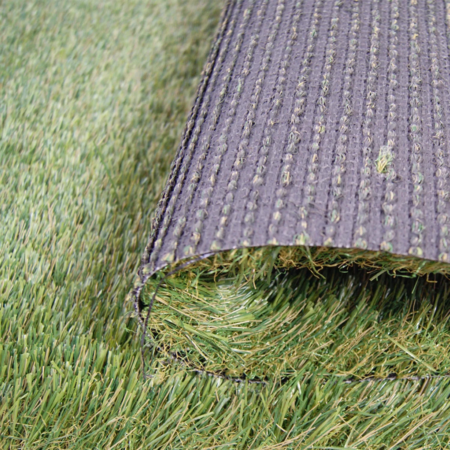 Un rouleau de gazon synthétique dévoilant la structure inférieure noire avec des coutures régulières et des fibres vertes réalistes.