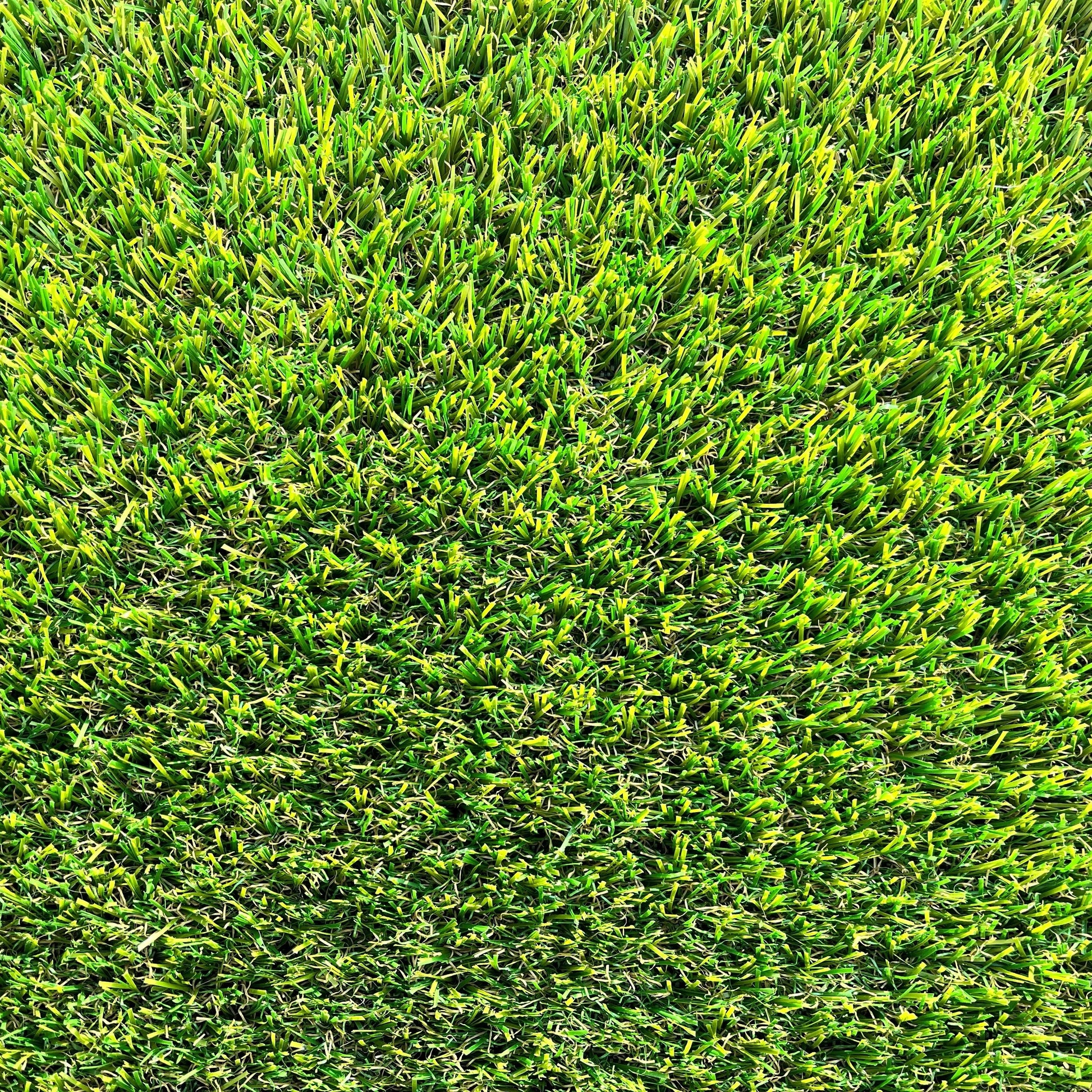  Une vue macro de brins de gazon synthétique, montrant les détails des fibres plastiques et leur base tissée noire, avec des nuances de vert et des touches de brun.
