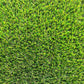  Une vue macro de brins de gazon synthétique, montrant les détails des fibres plastiques et leur base tissée noire, avec des nuances de vert et des touches de brun.