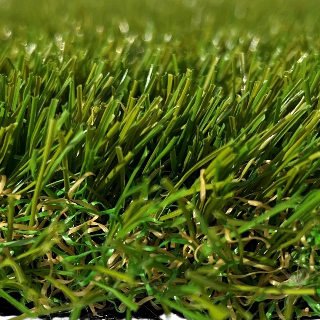 Vue rapprochée de brins d’herbe synthétique, montrant la texture réaliste et les différents tons de vert.