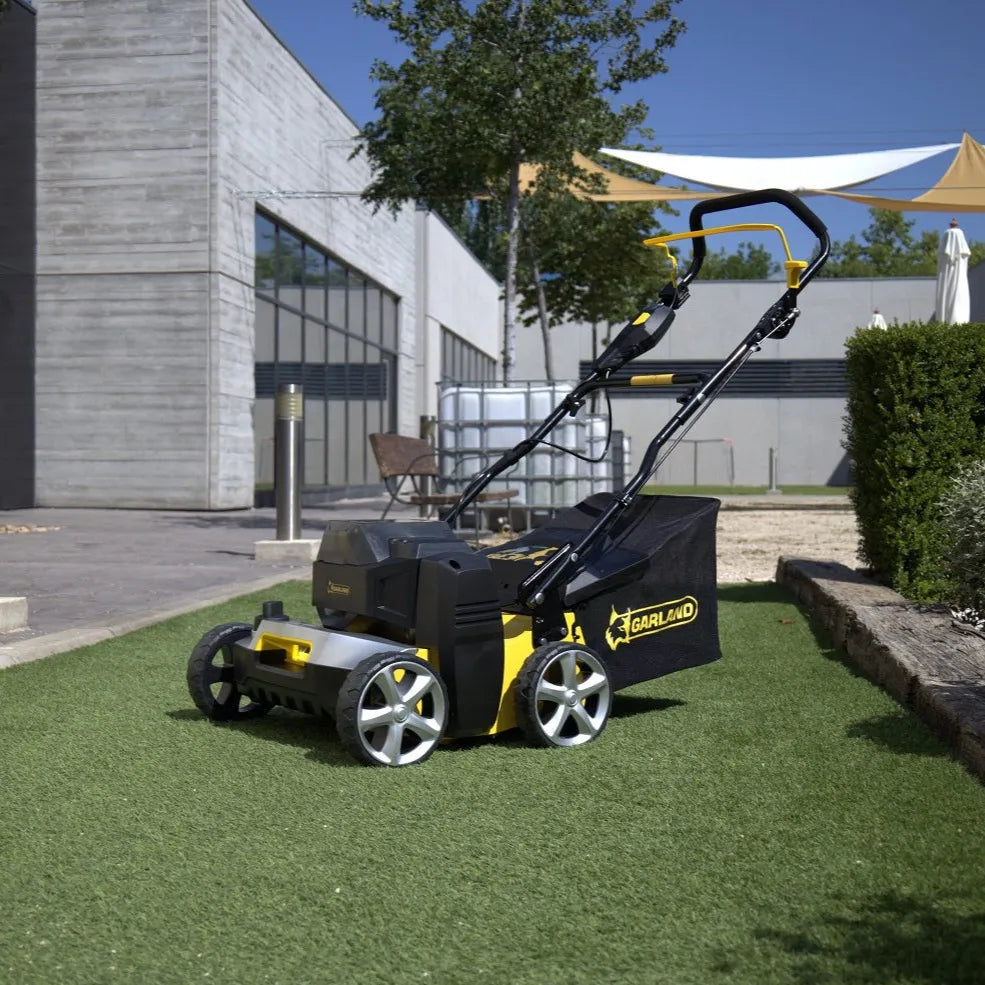 Brosse électrique Garland Comber 602E en utilisation dans un jardin, sur gazon synthétique.