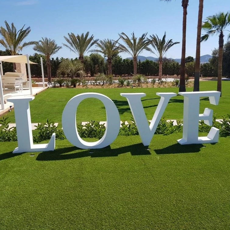 Gros plan sur le gazon vert-bleu de qualité supérieure Zoysia Empire. Des lettres L O V E  sont disposée sur le gazon en plein milieu d'un jardin, située au coté droit d'une maison californienne.